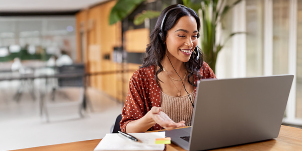 Smiling woman wearning headphones working at a laptop computer
