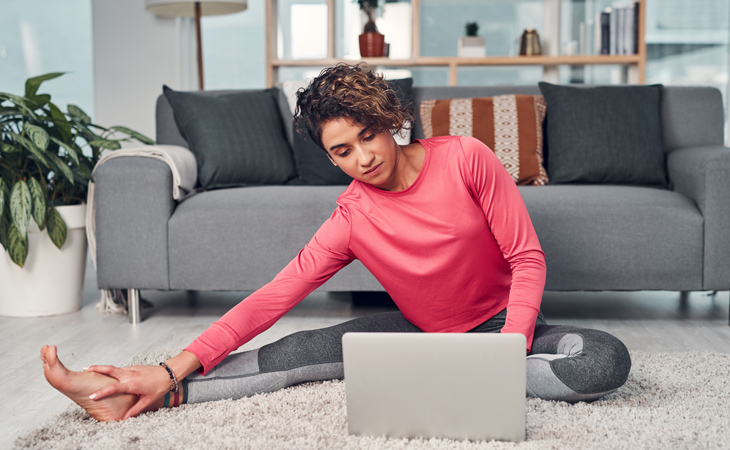 Woman stretching in front of a laptop