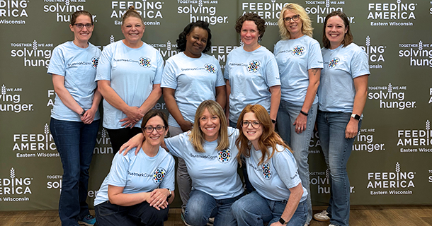 Large group of employees standing in front of a Feeding America backdrop.