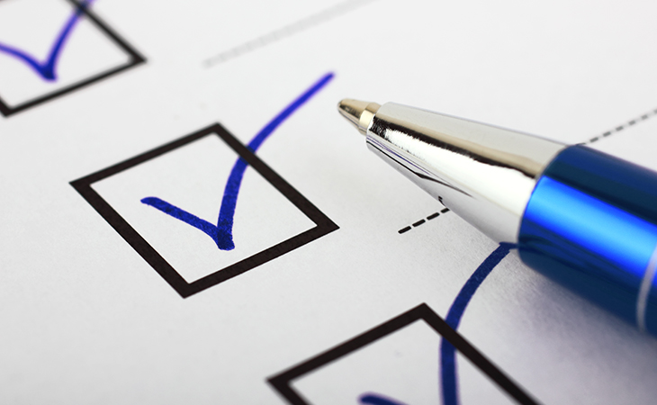 Pen resting on paper with checkmarks in boxes