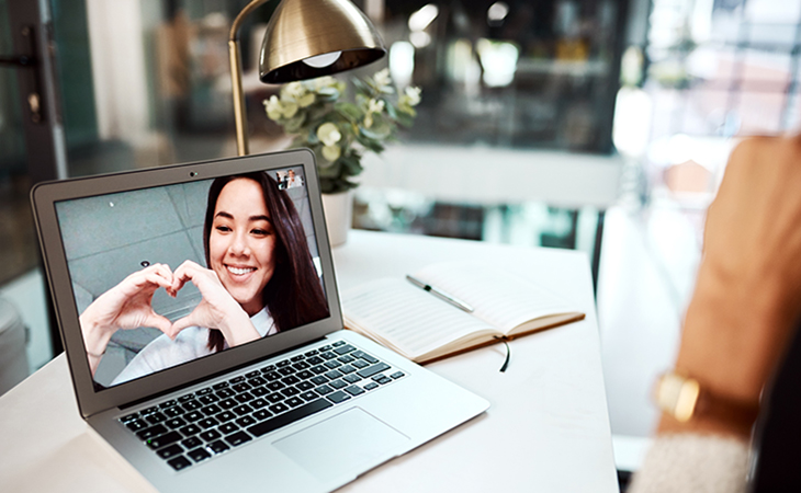 Laptop with image of a young woman making a heart shape with her hands