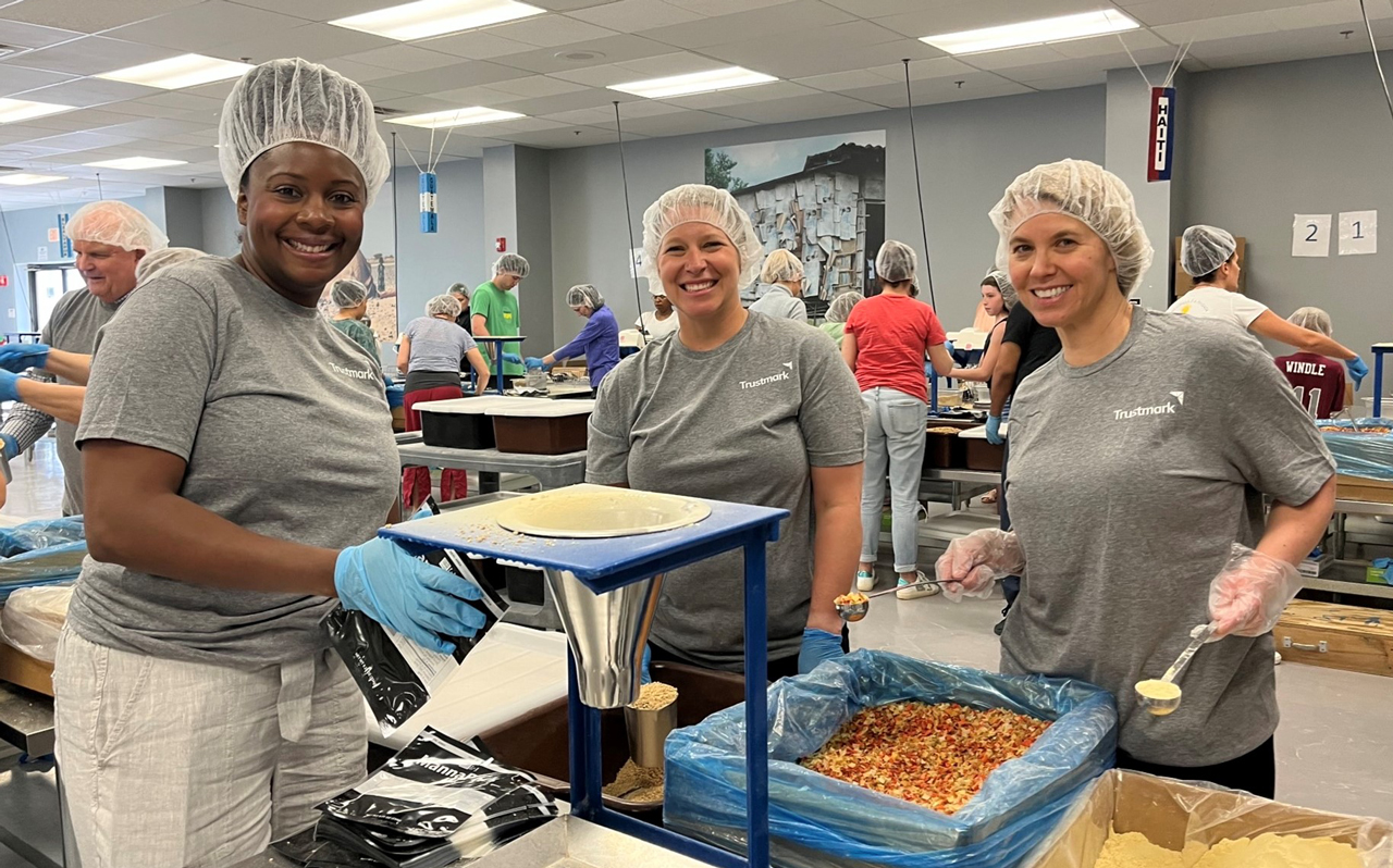 Three Trustmark associates preparing food as part of Community Week.