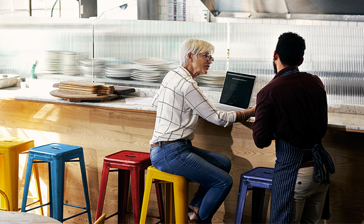 Woman and man sitting at a restaurant counter discussing business