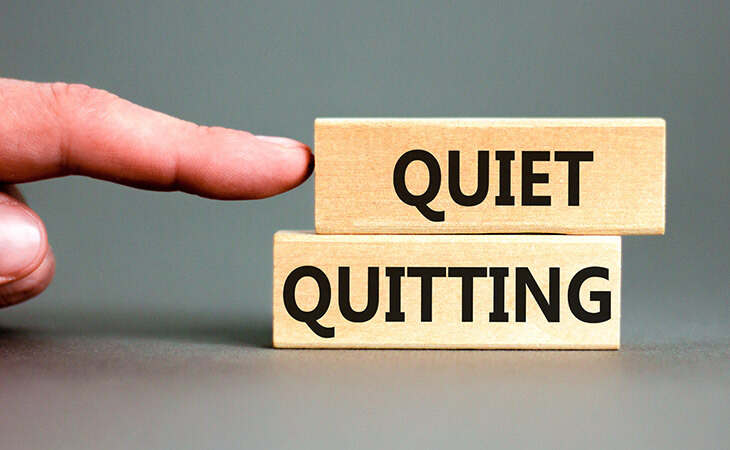 Finger pointing at blocks that read Quiet Quitting.