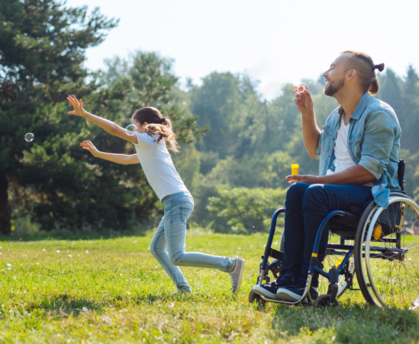man on a wheelchair is blowing bubbles and playing with a child 