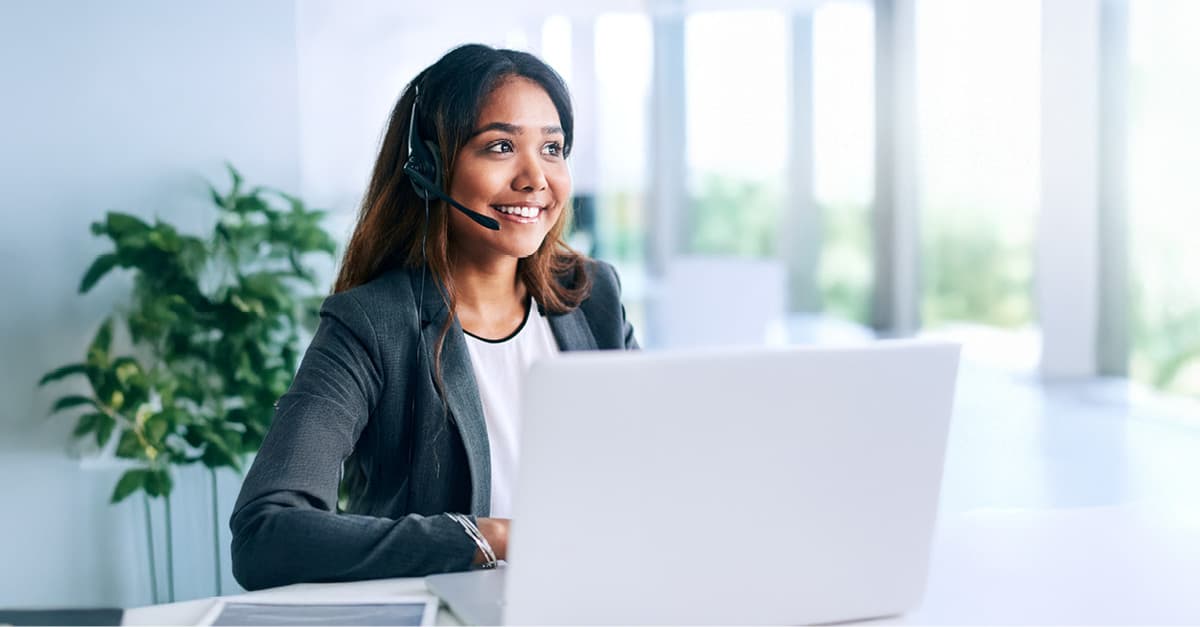 WOman wearing a headset in front of a laptop.