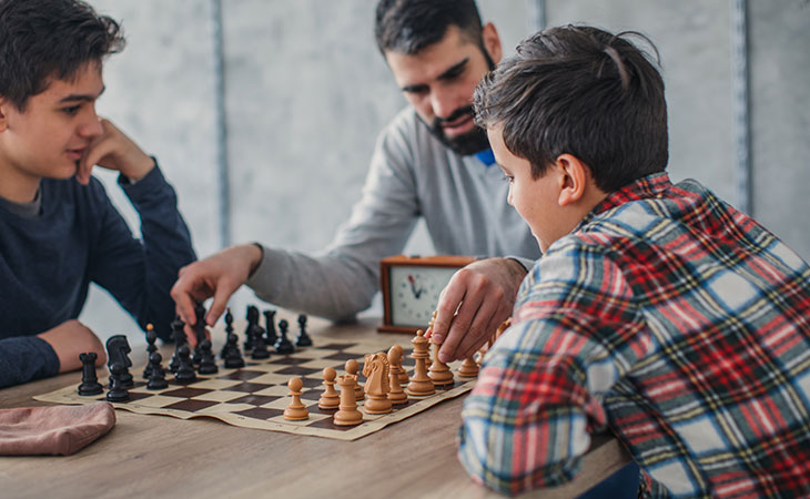 Father teaching sons the game of Chess.