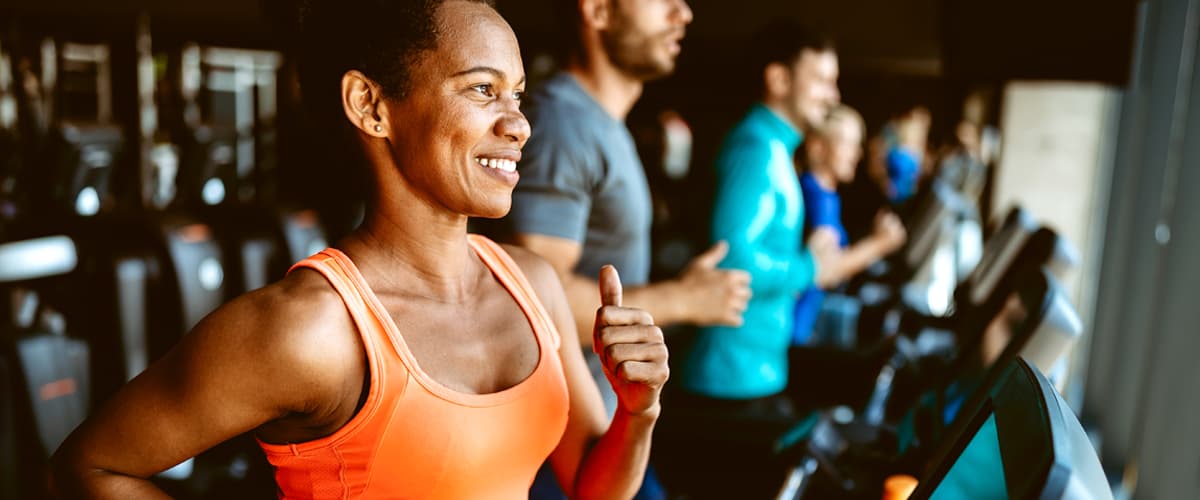 
A happy woman running on a treadmill in a gym.